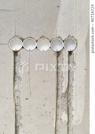 Holes in a concrete wall for installing plastic boxes under sockets. installation of sockets in a concrete wall and wiring. Holes in a concrete wall for installing plastic boxes under sockets. installation of sockets in a concrete wall and wiring. 90716724