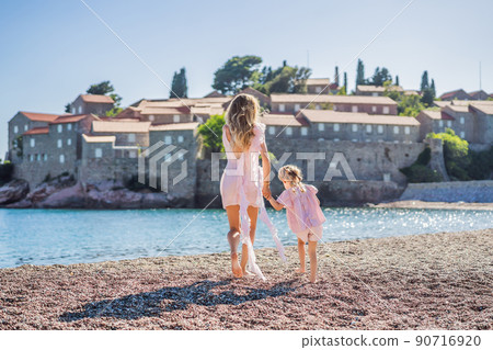 Mother and daughter tourists on background of beautiful view St. Stephen island, Sveti Stefan on the Budva Riviera, Budva, Montenegro. Travel to Montenegro concept 90716920