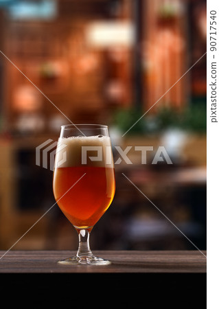 Tulip glass of beer on counter in pub. 90717540