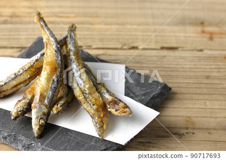 Fried silver-stripe round herring on slate plate and top paper Fried silver-stripe round herring on slate plate and top paper 90717693