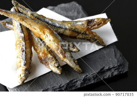 Slate plate, fried silver-stripe round herring on top paper taken on a black background 90717835