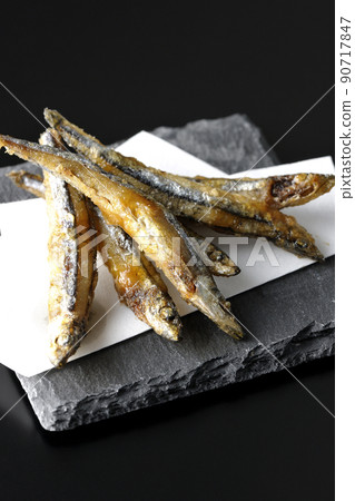 Slate plate, fried silver-stripe round herring on top paper taken on a black background 90717847