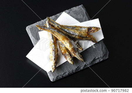A bird's-eye view of fried silver-stripe round herring on a slate plate and top paper with a black background A bird's-eye view of fried silver-stripe round herring on a slate plate and top paper with a black background 90717982