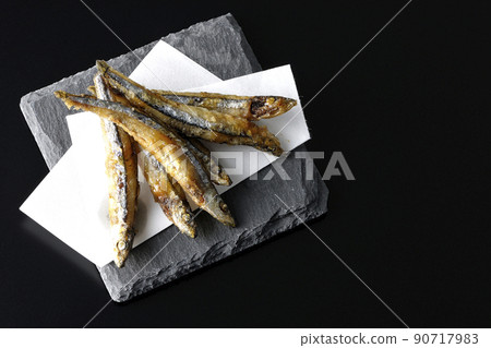 A bird's-eye view of fried silver-stripe round herring on a slate plate and top paper with a black background A bird's-eye view of fried silver-stripe round herring on a slate plate and top paper with a black background 90717983