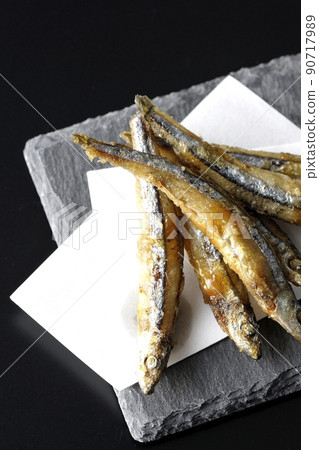 A bird's-eye view of fried silver-stripe round herring on a slate plate and top paper with a black background A bird's-eye view of fried silver-stripe round herring on a slate plate and top paper with a black background 90717989