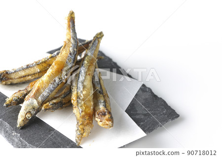 Slate plate, fried silver-stripe round herring on top paper taken on a white background Slate plate, fried silver-stripe round herring on top paper taken on a white background 90718012