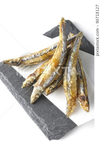 A bird's-eye view of fried silver-stripe round herring on a slate plate and top paper on a white background A bird's-eye view of fried silver-stripe round herring on a slate plate and top paper on a white background 90718127
