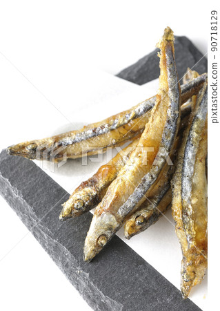 A bird's-eye view of fried silver-stripe round herring on a slate plate and top paper on a white background A bird's-eye view of fried silver-stripe round herring on a slate plate and top paper on a white background 90718129