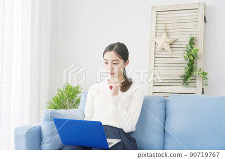 A woman sitting on the sofa in the living room and using a laptop 90719767