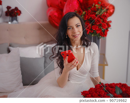 young woman in white dres is sitting on bed. young woman in white dres is sitting on bed. 90719982