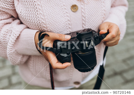 Woman photographer with a large professional camera takes pictures. Close up female hands hold black camera Woman photographer with a large professional camera takes pictures. Close up female hands hold black camera 90720146