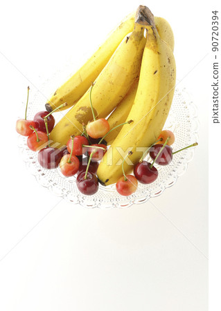 A bunch of bananas on the cake stand and lots of cherries. Photo assorted fruits on a white background A bunch of bananas on the cake stand and lots of cherries. Photo assorted fruits on a white background 90720394
