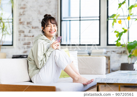 年輕女子在客廳看智慧型手機 90720561