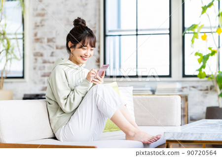 年輕女子在客廳看智慧型手機 90720564