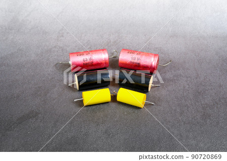 Bipolar capacitors of various sizes are arranged in a row on the cement floor background Bipolar capacitors of various sizes are arranged in a row on the cement floor background 90720869