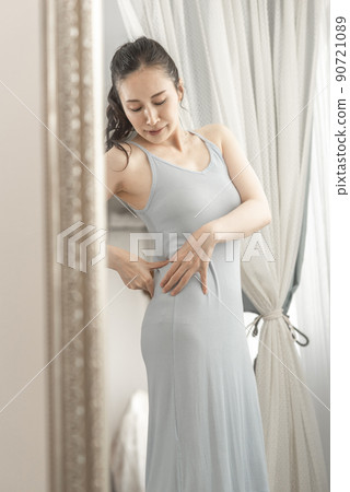A woman who cares about her body shape while looking in the mirror 90721089