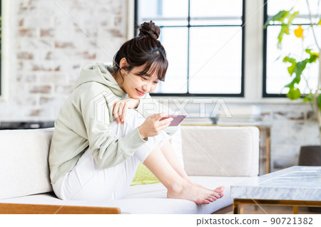年輕女子在客廳看智慧型手機 年輕女子在客廳看智慧型手機 90721382