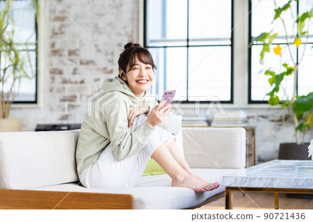 年輕女子在客廳看智慧型手機 年輕女子在客廳看智慧型手機 90721436