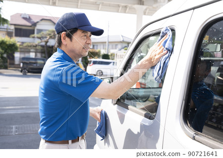 Elderly male worker wiping a car washed car 90721641