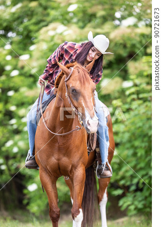 Woman riding a horse wearing a white hat communicates with the animal Woman riding a horse wearing a white hat communicates with the animal 90721673