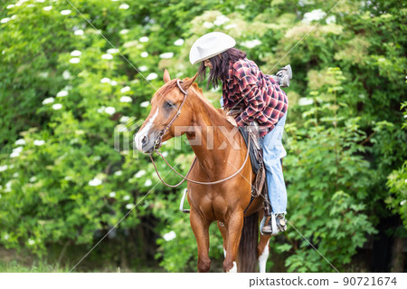 Woman getting off the horse with one foot still in the stirrup 90721674