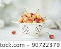 large ripe pink cherries in a white colander 90722379