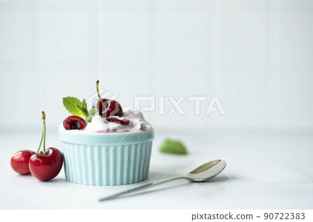 large cherries with homemade greek yogurt and mint in a blue bowl, copy space large cherries with homemade greek yogurt and mint in a blue bowl, copy space 90722383