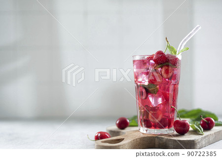cocktail with cherry juice, mint, and ice in a glass, copy space 90722385