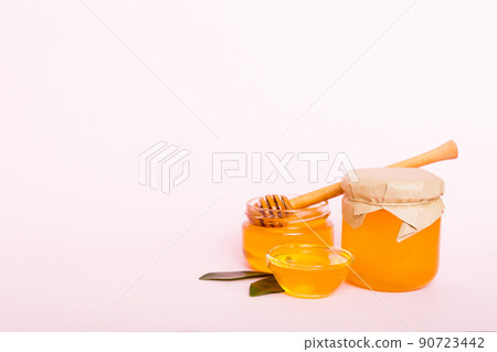 Honey in jar with leaves and honey dipper on colored background top view with copy text 90723442