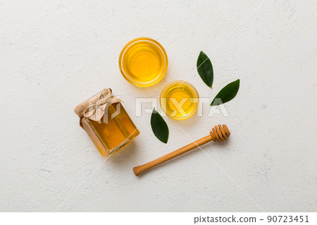 Honey jar with wooden honey dipper on white background top view with copy space. Delicious honey bottle Honey jar with wooden honey dipper on white background top view with copy space. Delicious honey bottle 90723451