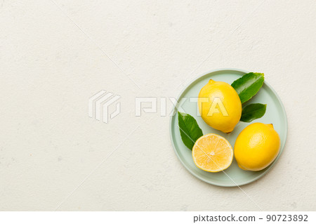 Fresh cutted lemon and whole lemons over round plate on colored background. Food and drink ingredients preparing. healthy eating theme top view vith copy space Fresh cutted lemon and whole lemons over round plate on colored background. Food and drink ingredients preparing. healthy eating theme top view vith copy space 90723892