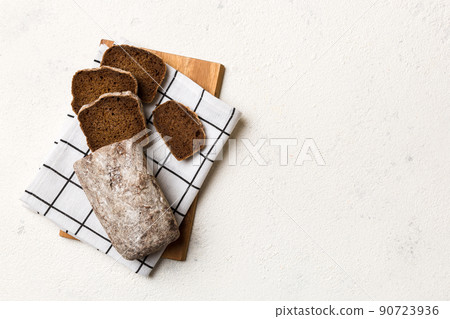 Freshly baked bread slices on cutting board against white wooden background. top view Sliced bread 90723936