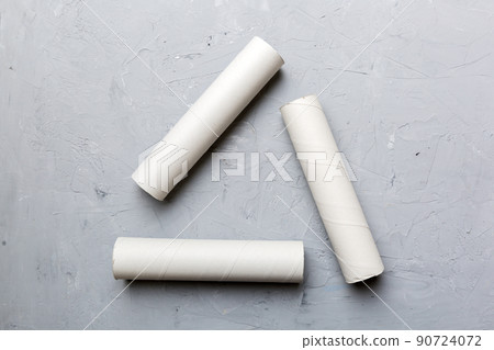 Empty toilet paper roll on colored background. Recyclable paper tube with metal plug end made of kraft paper or cardboard in the form of a recycling sign 90724072