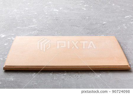 Perspective view of wooden cutting board on cement background. Empty space for your design 90724098