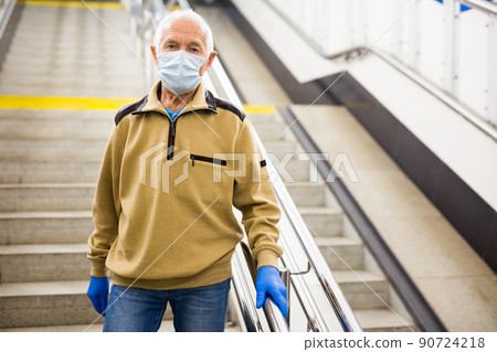 Elderly man in mask going down stairs to metro station 90724218
