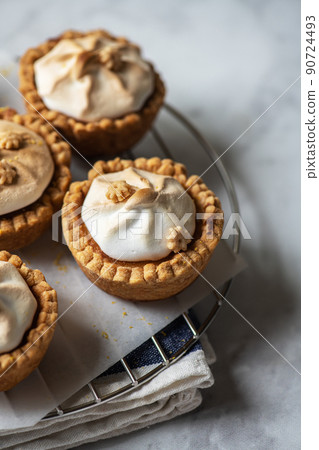 Lemon curd tartlets with whipped meringue on a wire rack. Close up. 90724493