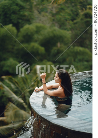Woman hanging out in the swimming pool. Lady in a swimsuit. Girl relaxing at a beach club in Bali Indonesia 90724720