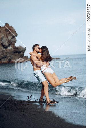 couple relaxing at a secluded private beach in Bali Indonesia. couple showing affection on a hidden beach. Couple wearing bathingsuits couple relaxing at a secluded private beach in Bali Indonesia. couple showing affection on a hidden beach. Couple wearing bathingsuits 90724757