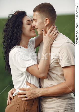 Couple in a field. Brunette in a white t-shirt. Pair walks. Couple in a field. Brunette in a white t-shirt. Pair walks. 90724879