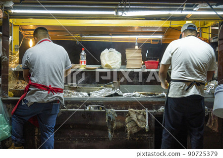 Open air Mexican taqueria Street food Restaurant Where two Mexicans are making tacos and quesadillas 90725379