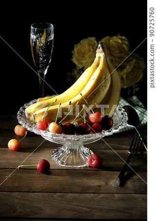 A bunch of bananas on the cake stand and lots of cherries. Assorted fruits, champagne and bouquet 90725760
