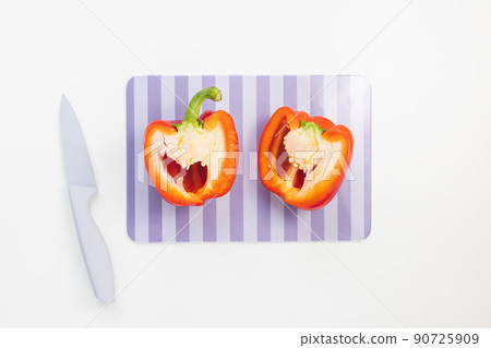 Fresh organic ripe sweet red bell pepper cut in half on cutting board with knife on white background Fresh organic ripe sweet red bell pepper cut in half on cutting board with knife on white background 90725909