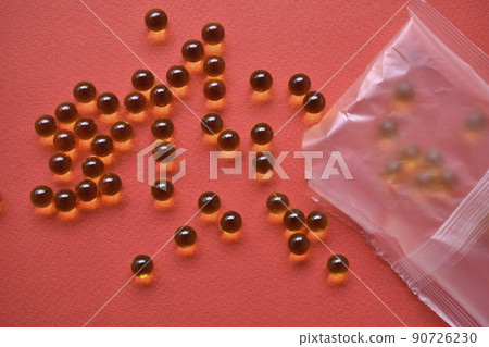 Yellow fish oil balls in a bag on a red background Yellow fish oil balls in a bag on a red background 90726230