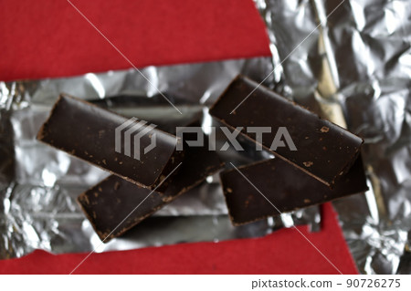 Chocolates on foil on a red background. Delicious candies. Chocolates on foil on a red background. Delicious candies. 90726275