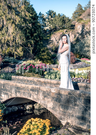 White Caucasian Adult Woman in a Wedding Dress standing outside in nature White Caucasian Adult Woman in a Wedding Dress standing outside in nature 90728074