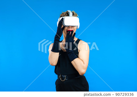 Surprised asian gay man with VR glasses posing isolated blue color background, Metaverse and Pride month Concept 90729336