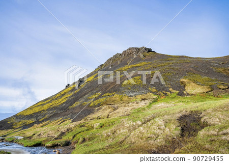 Majestic mountain by geothermal stream in Reykjadalur valley against blue sky Majestic mountain by geothermal stream in Reykjadalur valley against blue sky 90729455