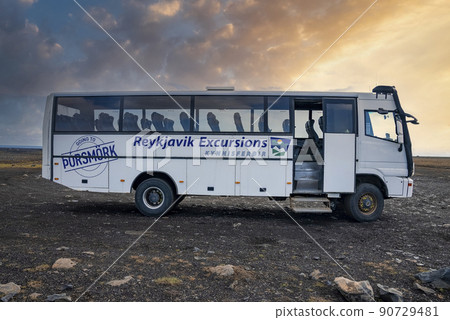Empty Reykjavik Excursions bus parked on lava sand against sky during sunset 90729481