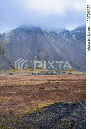 Distant view of Viking village under Vestrahorn mountain against cloudy sky 90729675