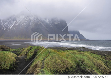 Beautiful grass on black beach against Stokksnes cape and Vestrahorn Mountain 90729742